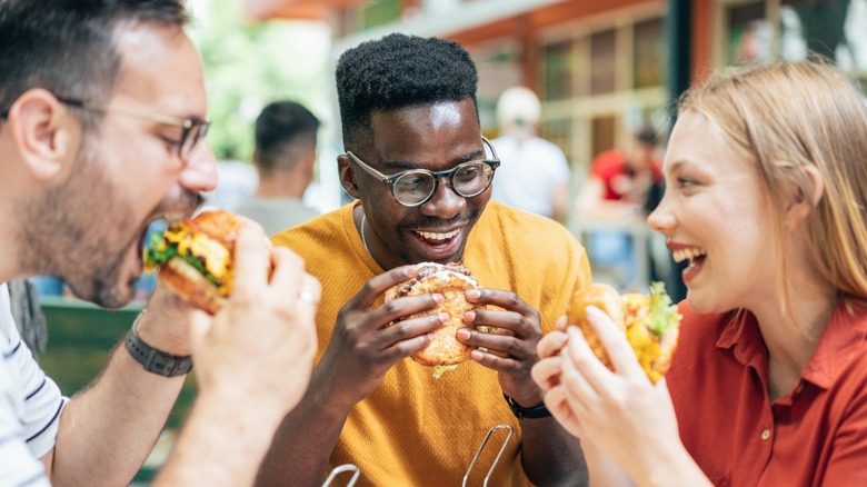 Friends eating burgers outside.
