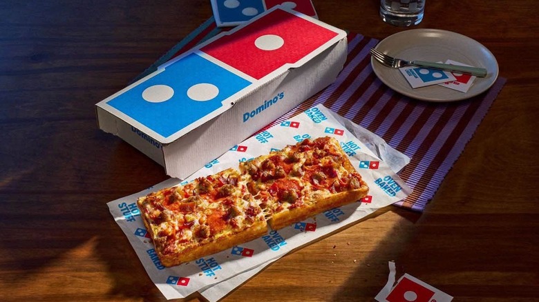 A pizza sits under a panel of light.