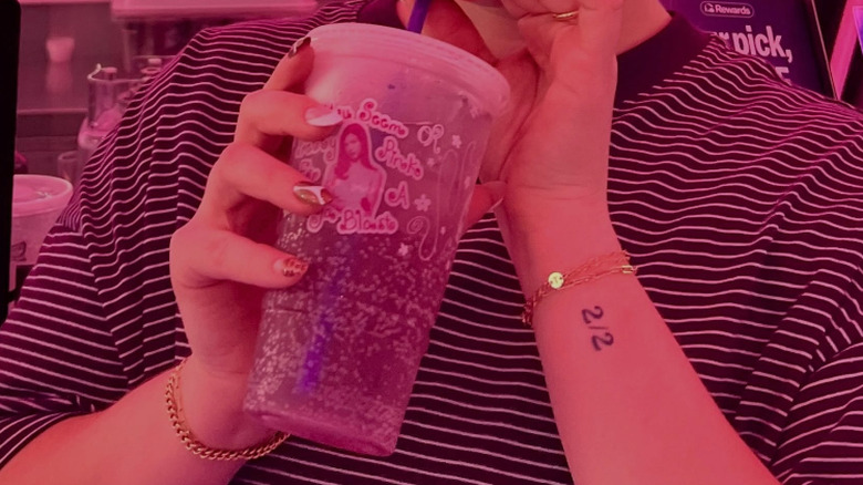 A woman sips from a pink soda.
