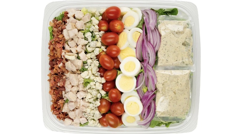 Ingredients for Member's Mark Cobb Salad arranged on a bed of greens in a plastic to-go container