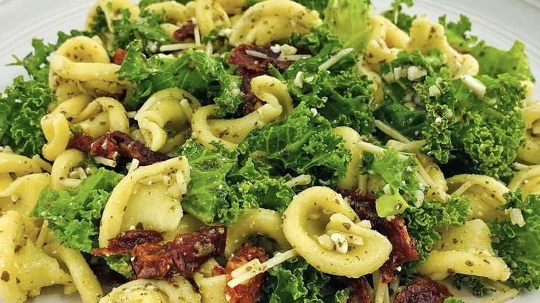 Kale, pasta, and sun-dried tomatoes sprinkled with grated cheese