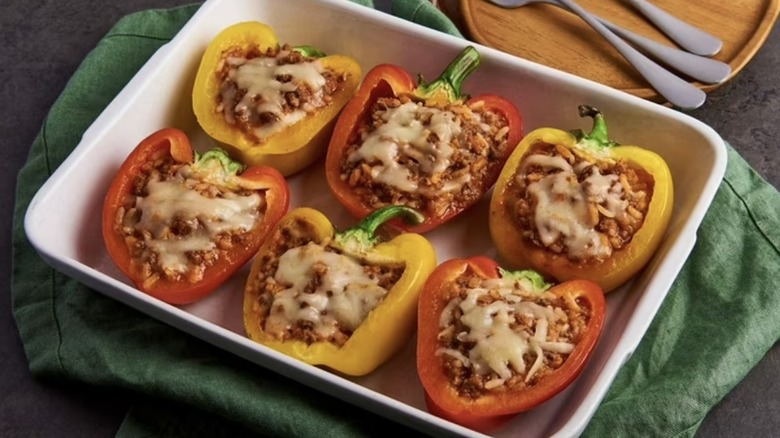 White baking dish filled with stuffed peppers set on a green cloth