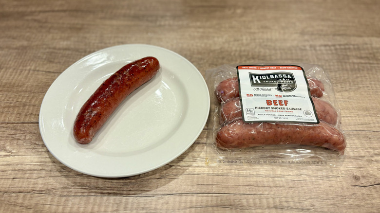 Kielbossa brand Hickory Smoked Beef Sausage on a white plate next to a package of the brand's sausages.