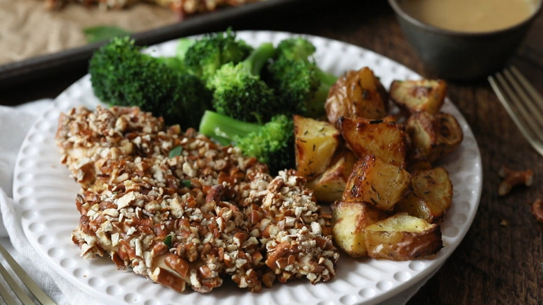 Pretzel breaded chicken cutlets next to home potatoes and broccoli.