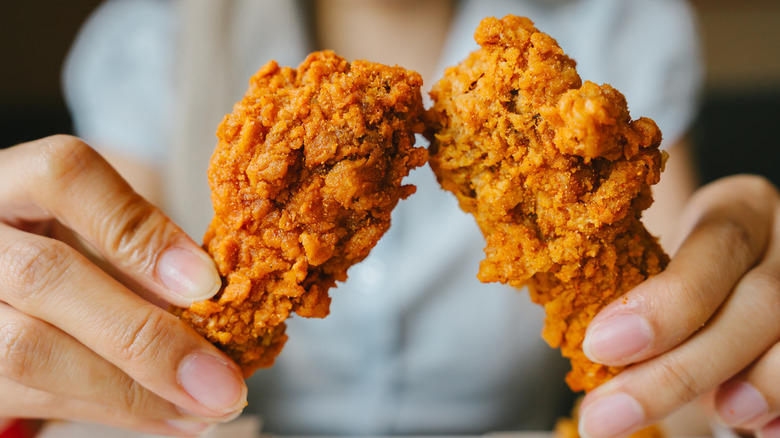 Person holding fried chicken in hands.