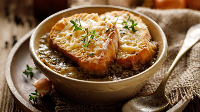 A bowl of French onion soup with cheese, bread, and fresh thyme