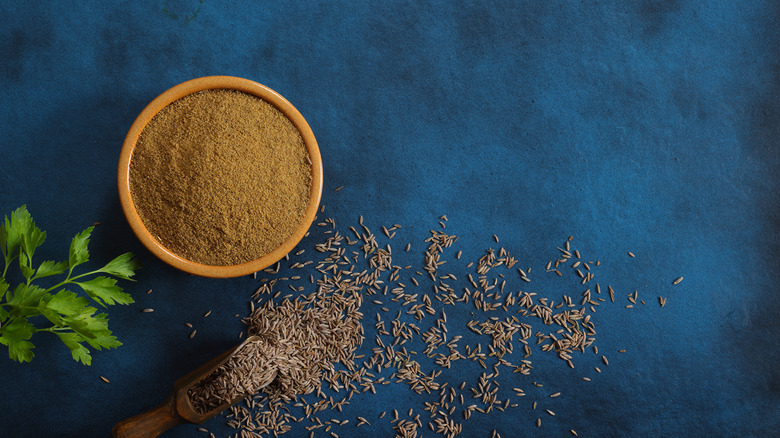 Bowl of cumin alongside cumin seeds