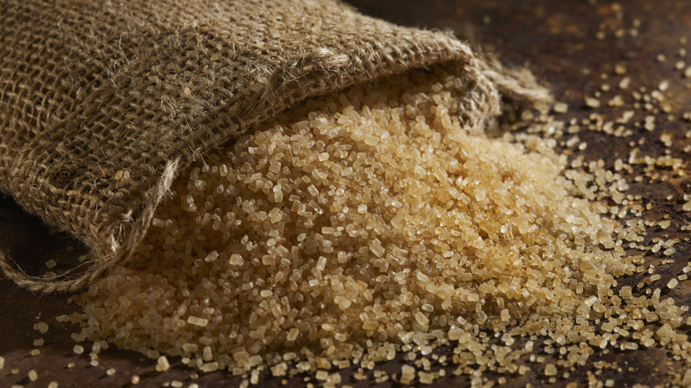 Burlap bag of raw sugar on its side with some spilling out