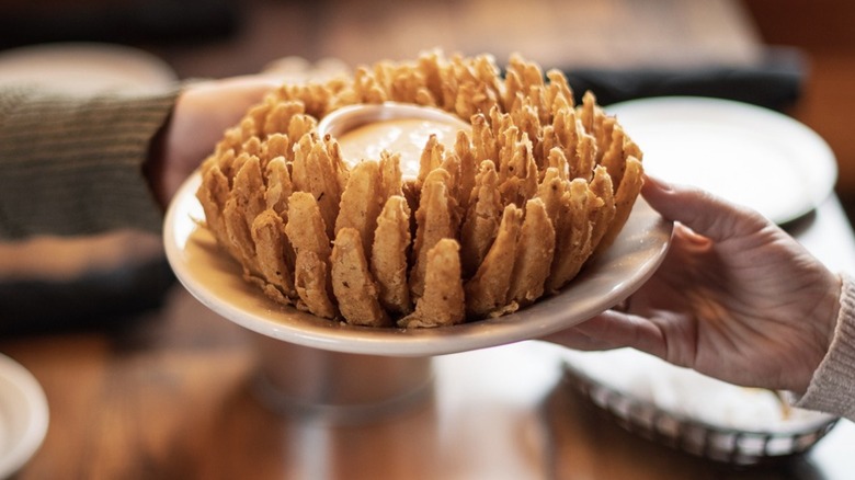Hands passing a Cactus Blossom across the table at a Texas Roadhouse