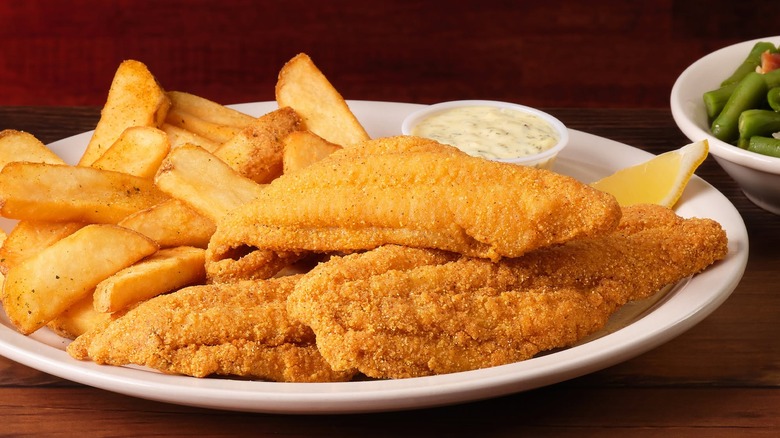 Platter loaded with Texas Roadhouse Fried Catfish, steak fries, and sauce served alongside green beans