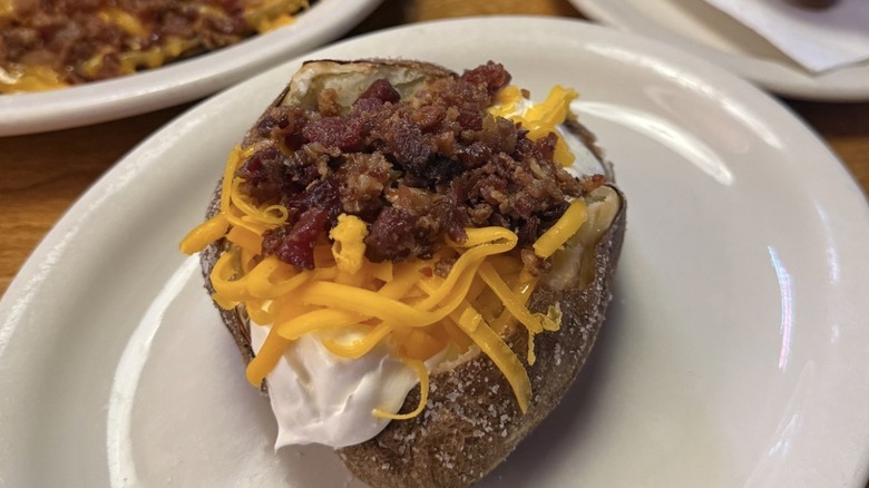 Texas Roadhouse baked potato topped with bacon bits, cheddar cheese, and sour cream