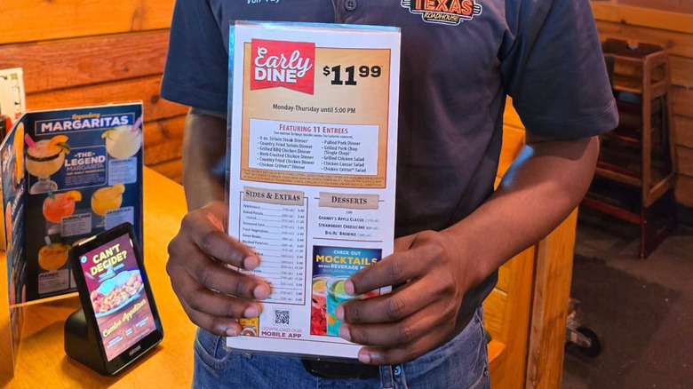Texas Roadhouse employee holding the Early Dine menu