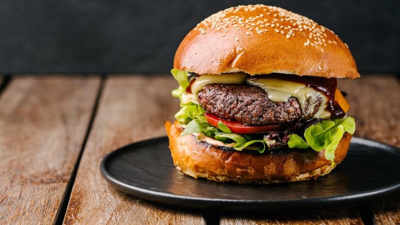 Meat-free cheeseburger on black plate on wooden table