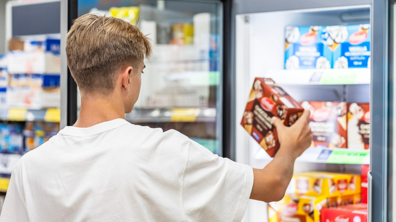 Man taking package out of freezer aisle in grocery store