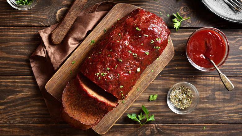 Meatloaf on cutting board with spicy tomato sauce