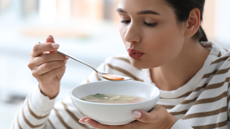 Woman blowing on soup
