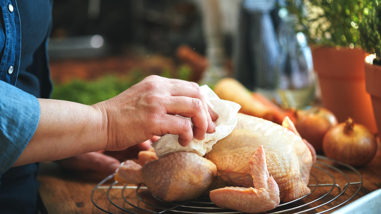 Someone preparing a raw whole chicken in a kitchen