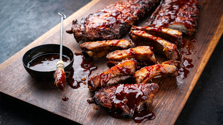 Rack of St. Louis-style BBQ ribs with sauce on wooden cutting board