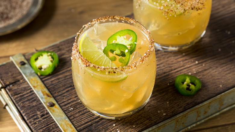 Spicy margaritas garnished with jalapeño and a red pepper salt rim