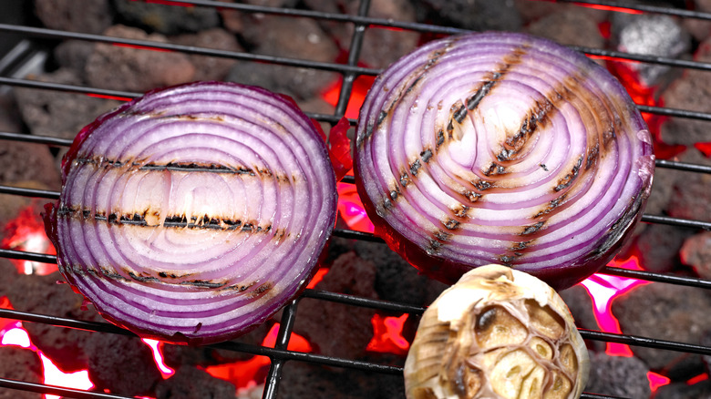 Red onion slices with skin on being grilled