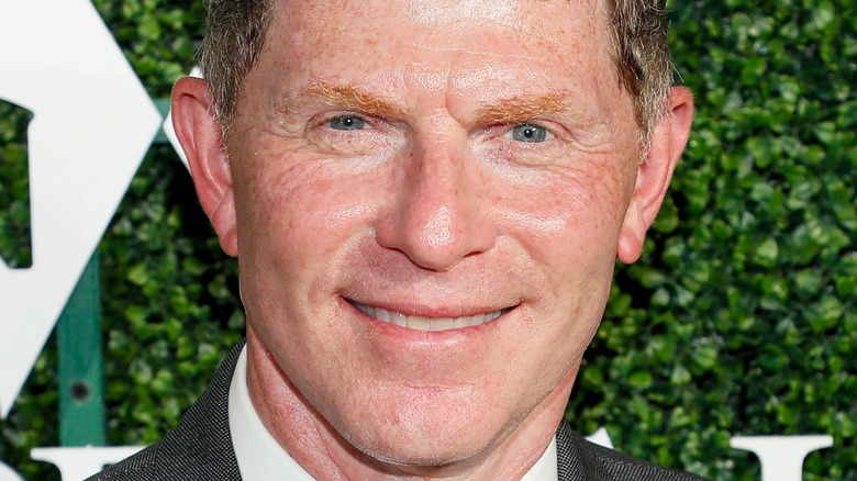Bobby Flay in front of green step-and-repeat backdrop