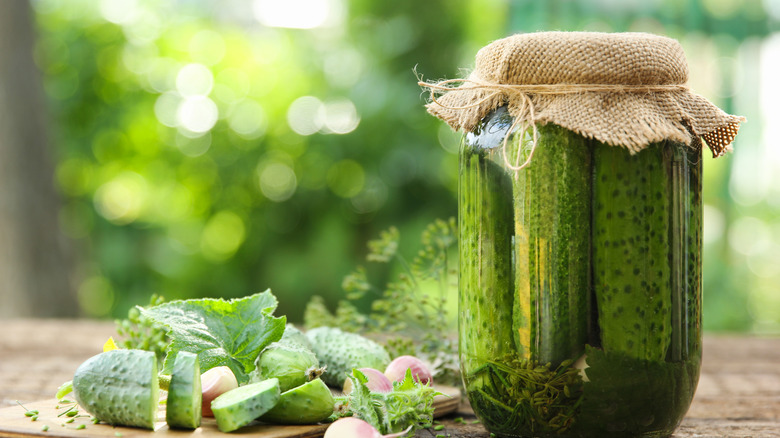 dill pickles and fresh cucumbers on wooden table