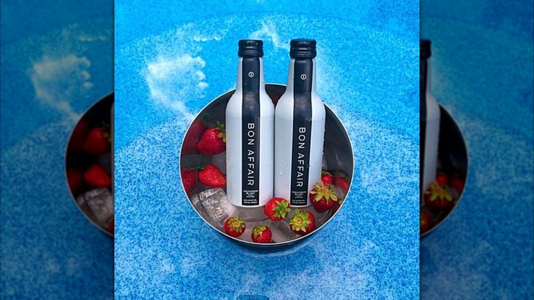Two bottles of Bon Affair in an ice bucket with strawberriess