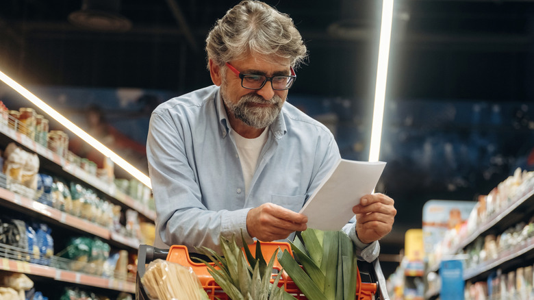A boomer reads a grocery list in the store.