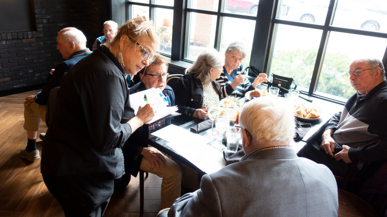 Group of boomers talking to a waitress at a restaurant