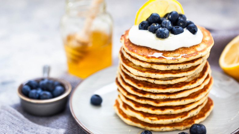 poppy seed pancakes topped with cream, blue berries, honey, and a wedge of lemon