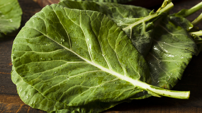 whole raw collard greens laid on a wooden surface