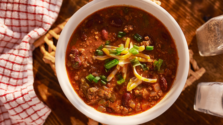 Overhead view of chili with cheese and green onions