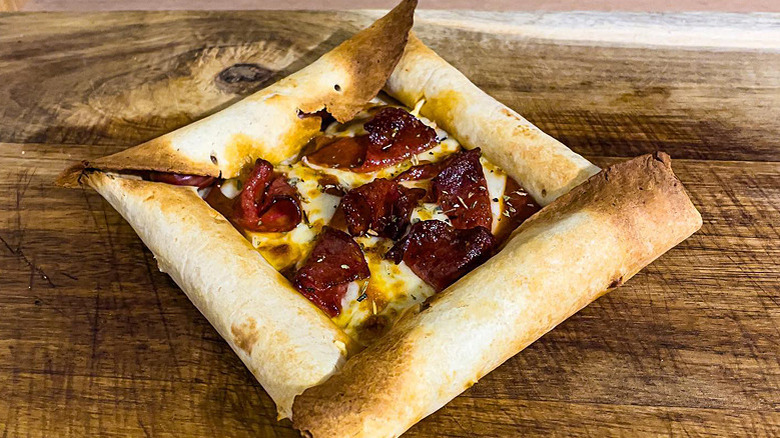 Stuffed crust tortilla pizza with melted cheese and pepperoni on wood countertop