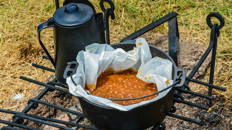 Boston baked beans in a crock, cooked outside on an open fire, next to a kettle of coffee