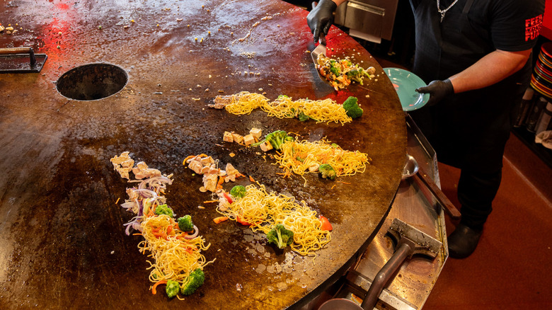 A grill cook prepares food on a round flat top at a Boston restaurant
