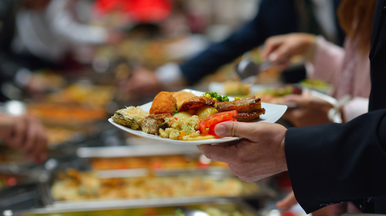 A person holds a plate of food from a buffet