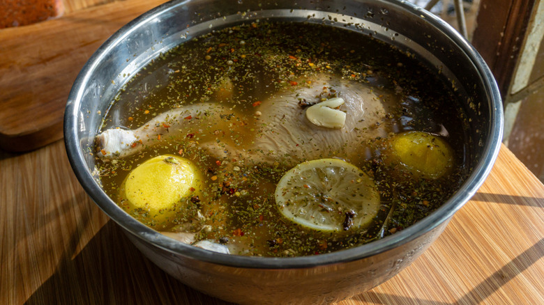 Soaking a chicken in a brine solution using lemon and herbs