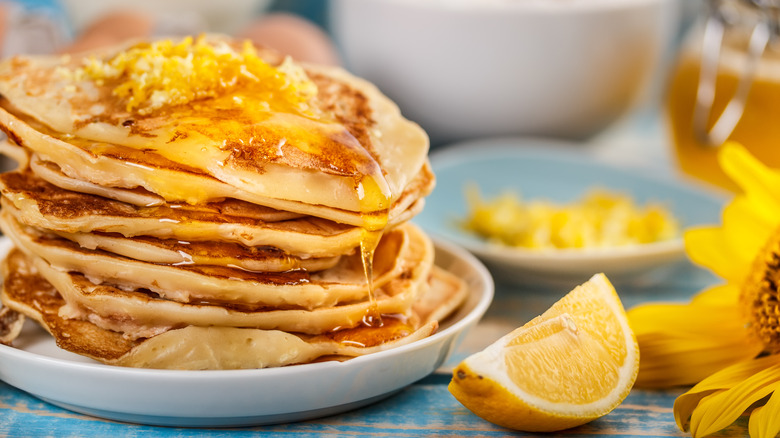 Pancakes topped with syrup and lemon zest by lemon wedge