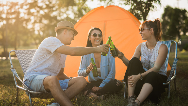 friends toasting beer at campsite tent