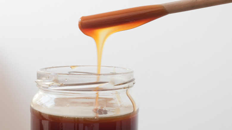 A stick covered in rice syrup over a jar of rice syrup