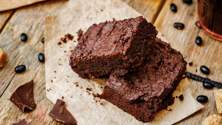 A pair of gooey brownies on a wooden table