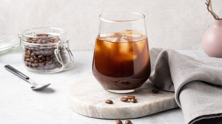 A glass of cold brew coffee with coffee beans
