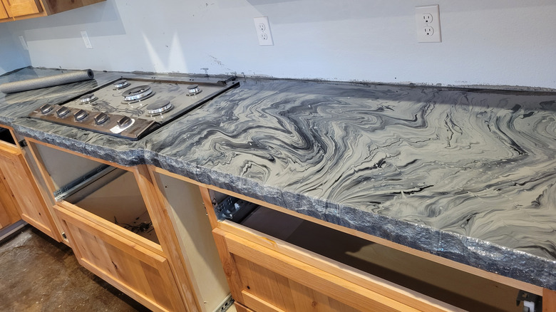 Concrete countertop with a swirly, marble-esque pattern and raw rock-like edge.
