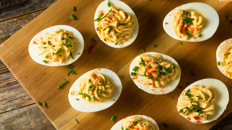 Deviled eggs on a wooden cutting board.