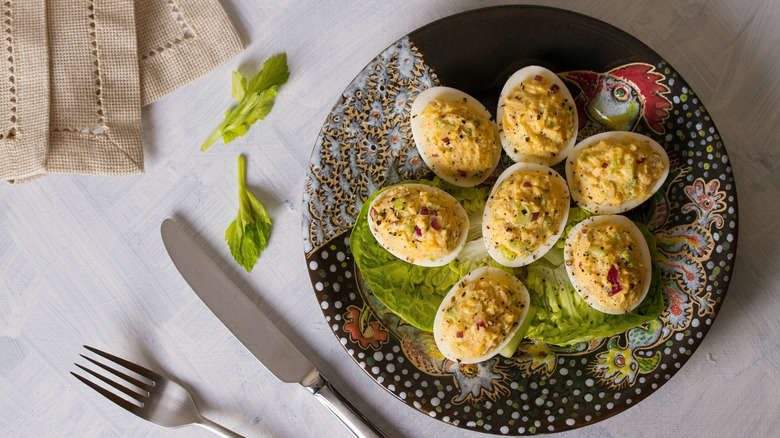 Tuna stuffed deviled eggs on a plate next to a fork and knife.