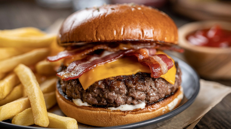 Bacon cheeseburger on a plate with fries