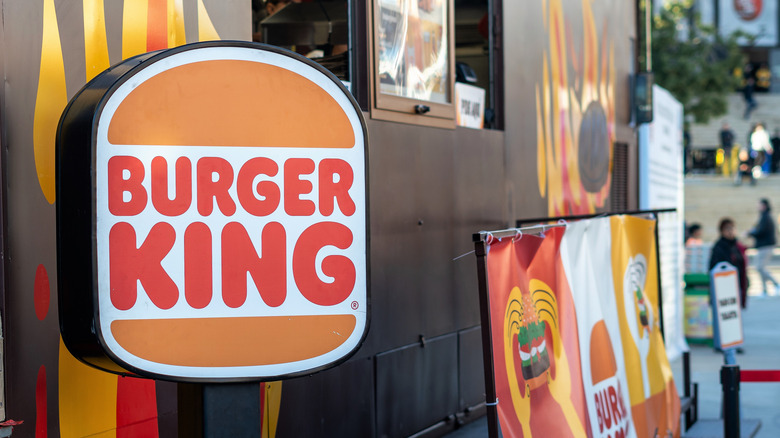 A Burger King sign is shown near a restaurant drive-thru window