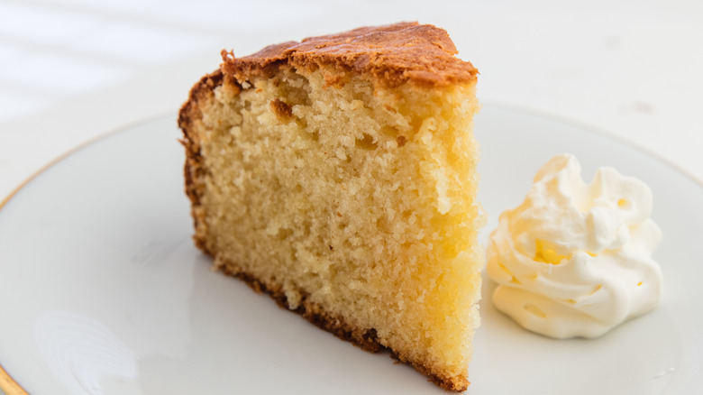 A slice of butter cake with a dollop of whipped cream on its plate