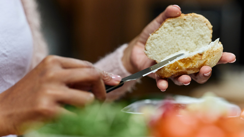 hands spreading butter on roll