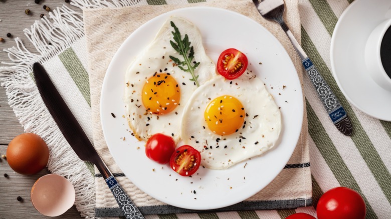 Fried eggs on plate with tomatoes 